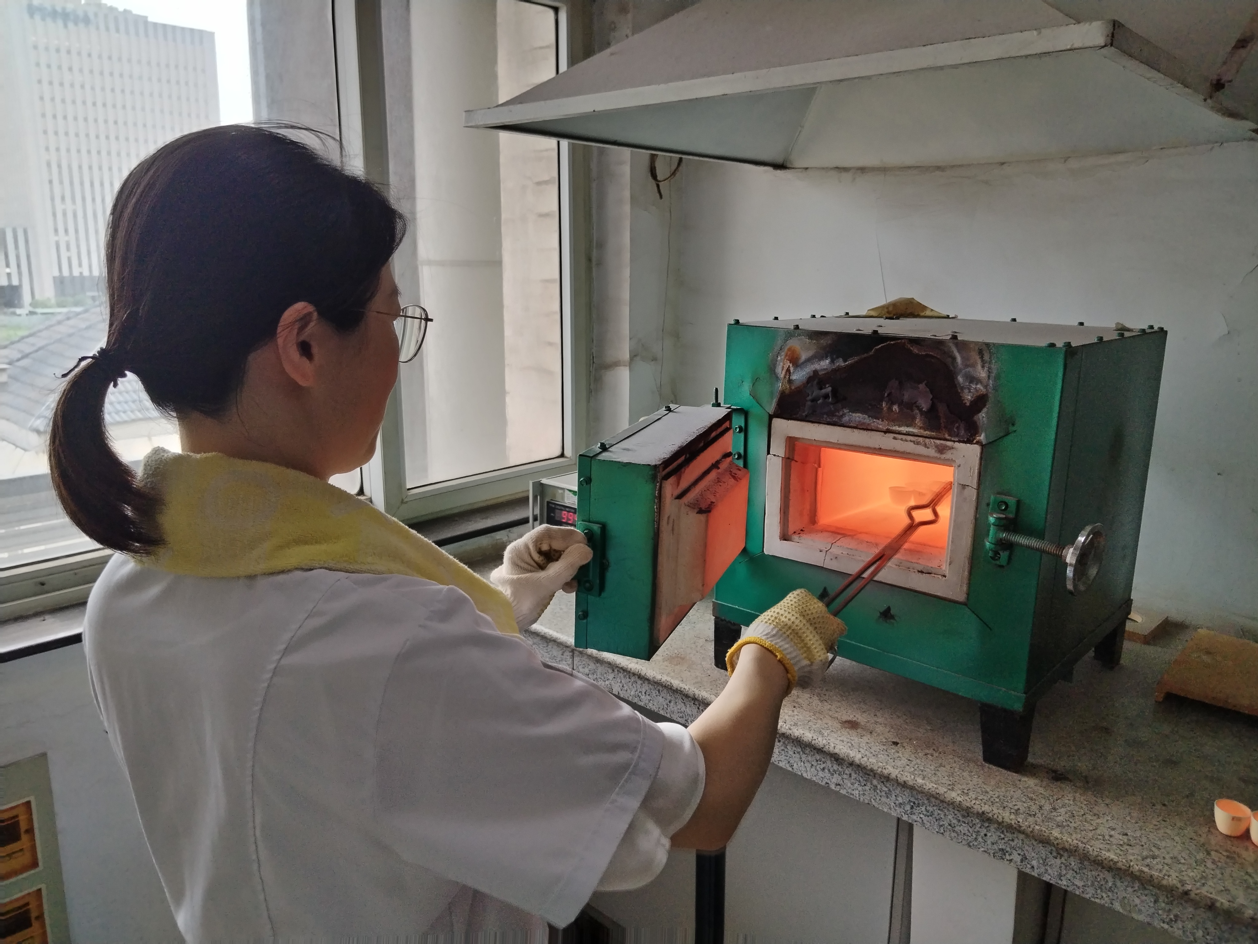 江苏省新沂市蒋庄-东海陈集地区超基性岩铬铁矿普查项目--硅酸盐岩石烧失量分析工作中，实验室同志正顶着酷暑将分析样品从1000多度的高温马弗炉中取出2.jpg